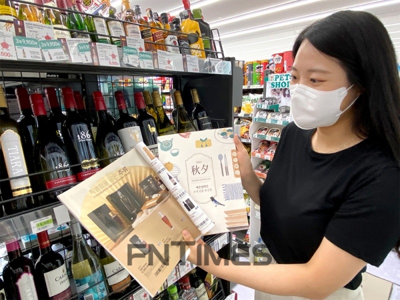 세븐일레븐 점원이 카탈로그를 통해 프리미엄 위스키를 주문받고 있다./사진=세븐일레븐