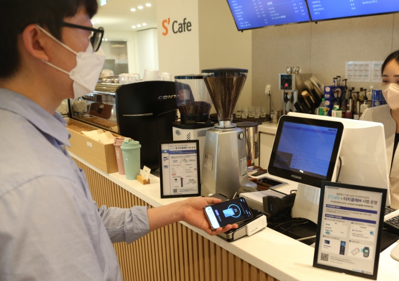 신한카드가 아이폰을 가맹점 결제 단말기에 갖다 대면 결제가 가능한 ‘신한카드 터치결제M’ 시범 서비스를 시작했다. 사진은 카페에서 한 직원이 '신한카드 터치결제M' 서비스로 음료를 주문하는 모습. /사진제공=신한카드