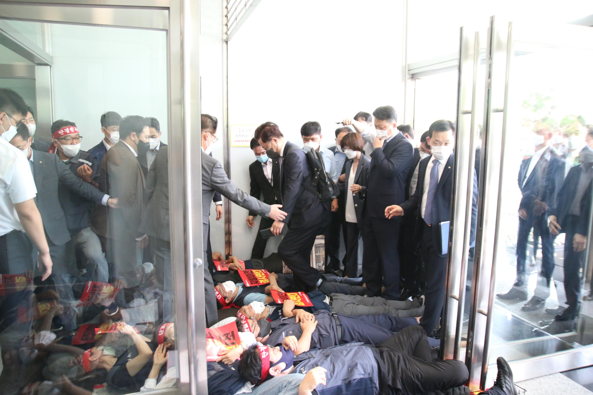 강석훈 KDB산업은행 회장이 21일 오전 서울 여의도 산은 본점에서 출근을 저지하기 위해 드러누운 노조원들을 넘어가고 있다. / 사진제공=전국금융노동조합