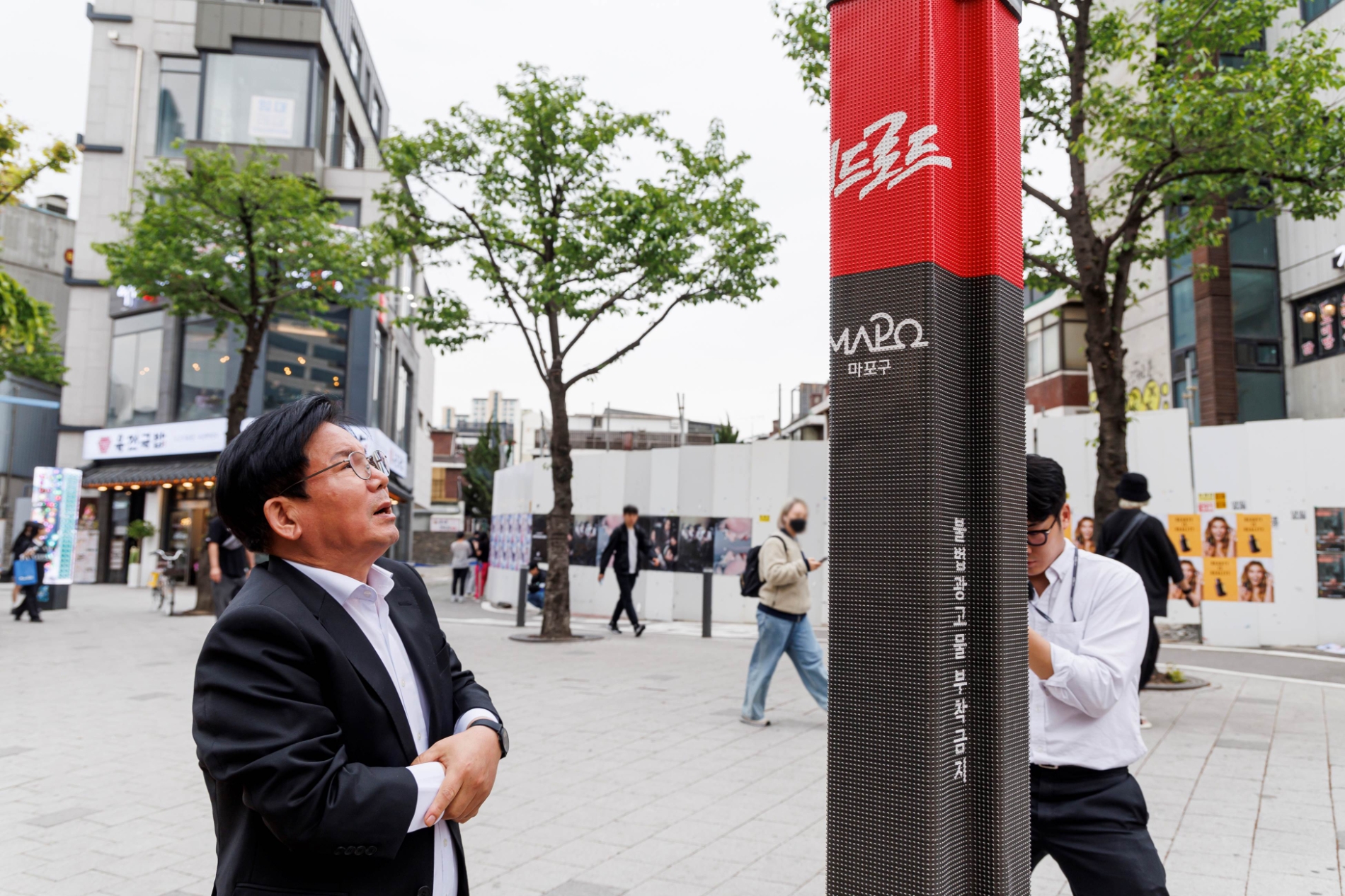 박강수 마포구청장이 지난 4월 말 홍대 레드로드의 전신주에 설치된 불법광고물 방지 시트를 살펴보고 있다./사진제공=마포구