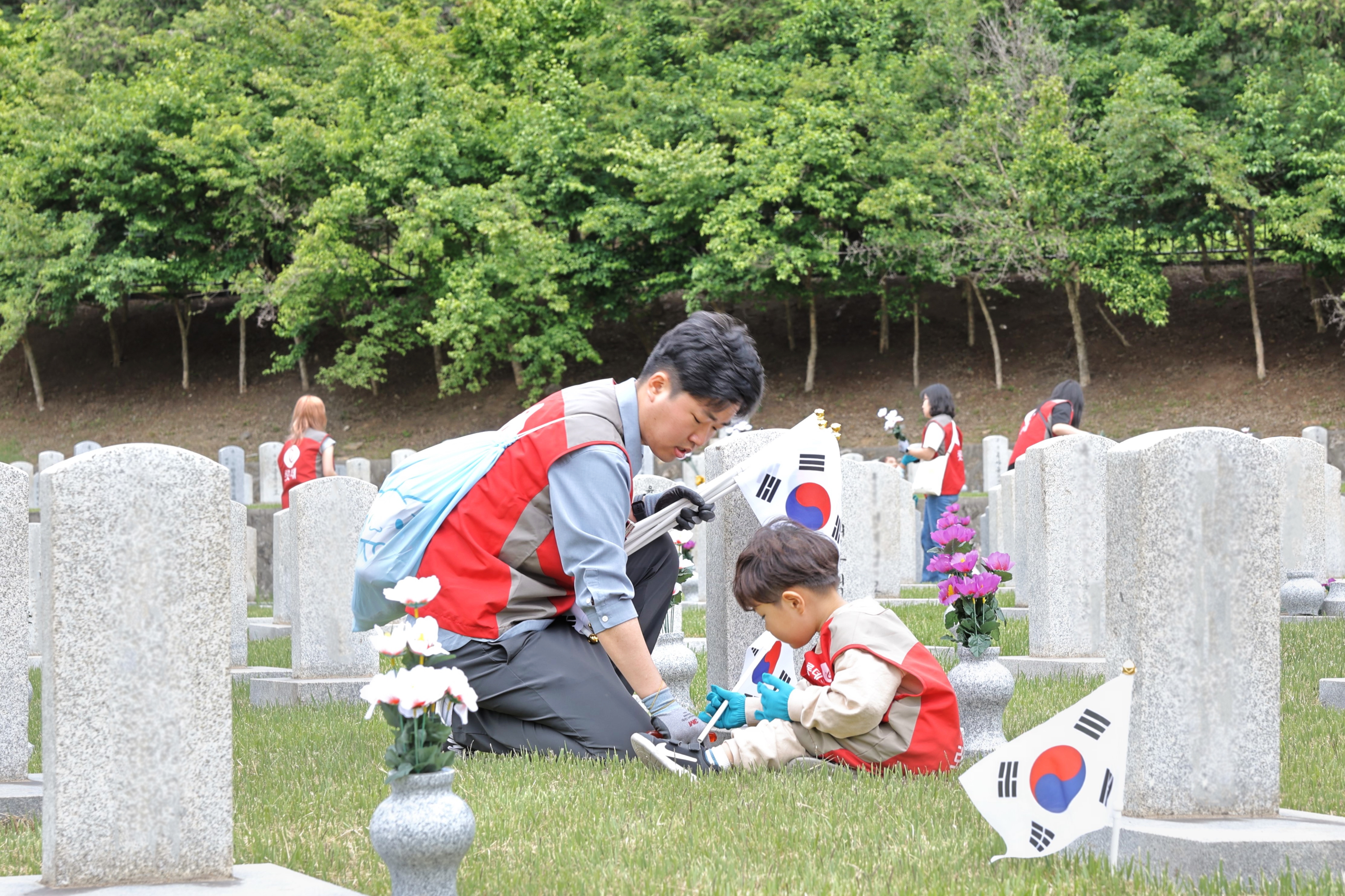 롯데건설 ‘샤롯데 봉사단’이 묘비 옆에 태극기를 꽂고 있다./사진제공=롯데건설